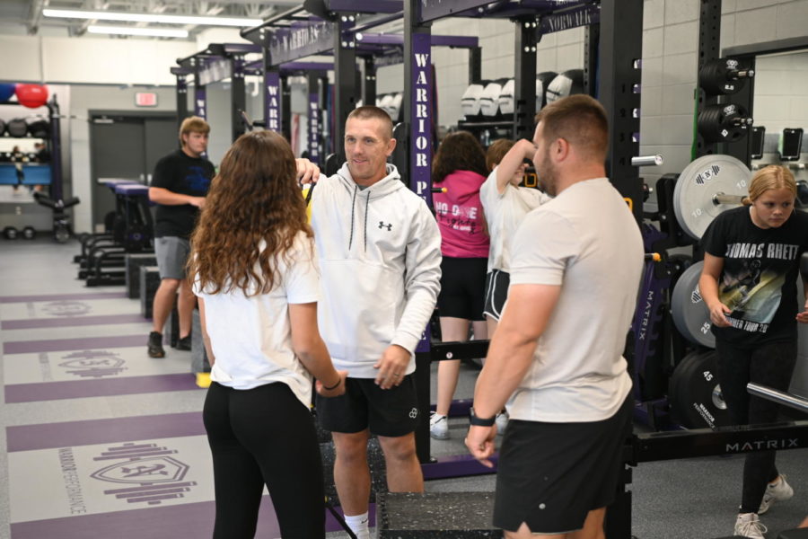Brandon Schmitz (center) and Cory Archer teach P.E. student Mariola Torra Abad how to use the new TRX band system during strength and conditioning. Many students are learning how to use the new NPECC equipment in the high school.