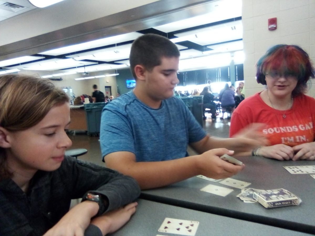 Middle school students Kaden Sammons (left) and Colin Campbell play cards with Ash Shelledy in the cafeteria on Aug. 29. Sammons and Campbell said they have done this every morning as a way to pass the time before school.