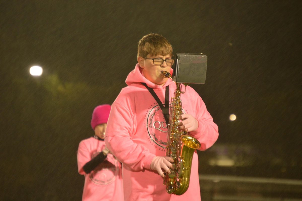 Jackson Bellbee plays alto saxophone for the 8th grade band on Friday, Oct. 13. The group wore pink shirts to represent their show during the annual pink-out game.