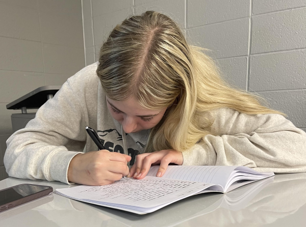 Junior Allie Soukup writes in her notebook during 4th period in January 2024. Soukup is a mentor involved in the MVP program at Norwalk High School.