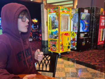 Norwalk Middle School student Sasha Rooney-Kozak at Jordan Creek mall on Dec. 26 2023. He is eating razzles before he enters the movie theater to watch Wonka. 
