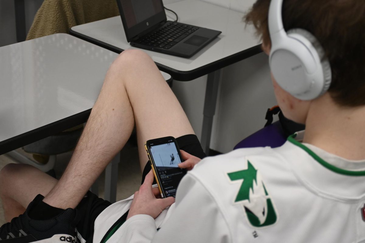 Senior Kyle Erickson watches hockey on his phone on Tuesday, Feb. 28, in journalism class. Erickson said Hockey is one of his favorite sports. 