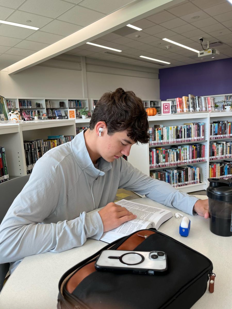 Junior Payton Miller reads his Bible during third period on Aug. 29 in the high school library. The library is a place students can go to during their release and college lab periods.