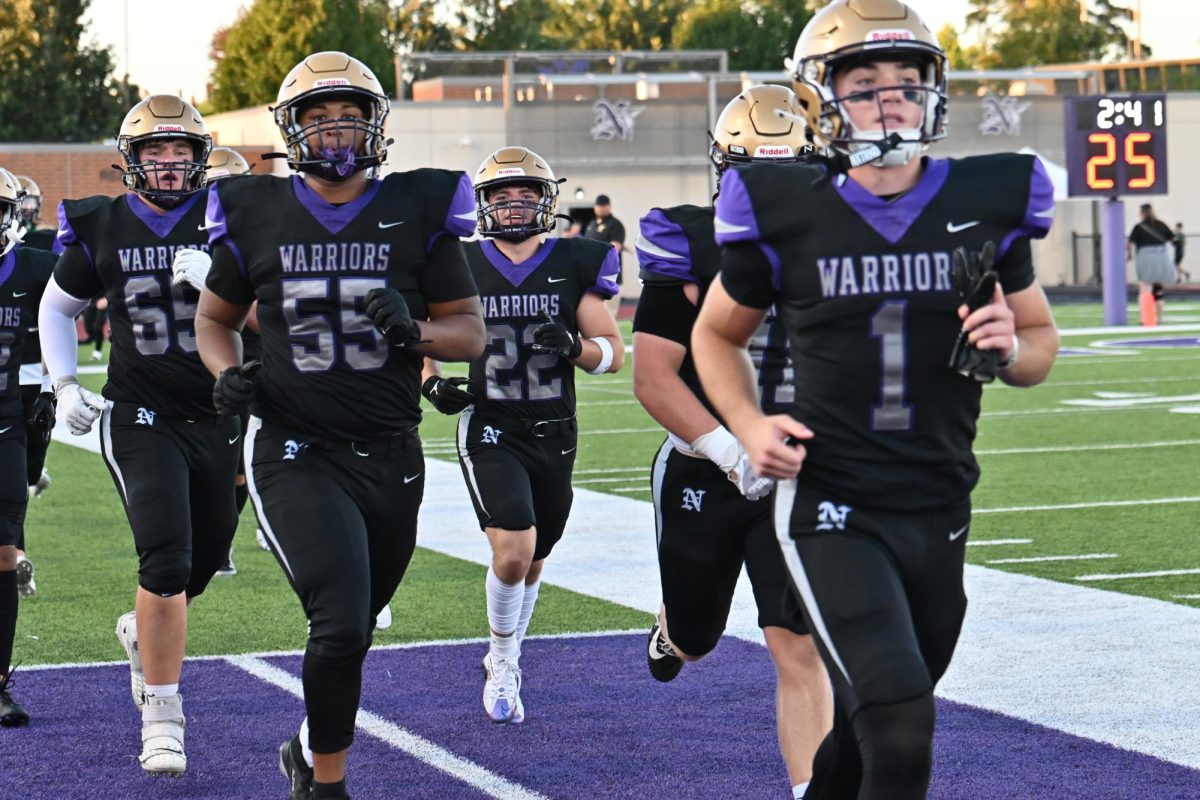 Eli Robbins (right) and the Norwalk Football Team run out onto the field for the game against Carlisle on Friday, Aug. 30.  The Warriors will face off against Newton on Friday, Sept. 13, for their Homecoming game. 