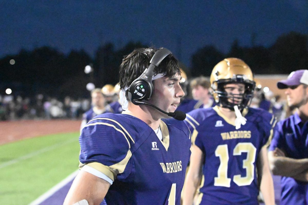 Junior Wide Receiver Eli Robbins (left) talks on the headset to the offensive coordinators on the sideline during the Homecoming game on Friday, Sept. 27. The Norwalk Warriors will take on the Dallas Center-Grimes Mustangs at 7 p.m. on Oct. 4 at Mineart Field in Norwalk.