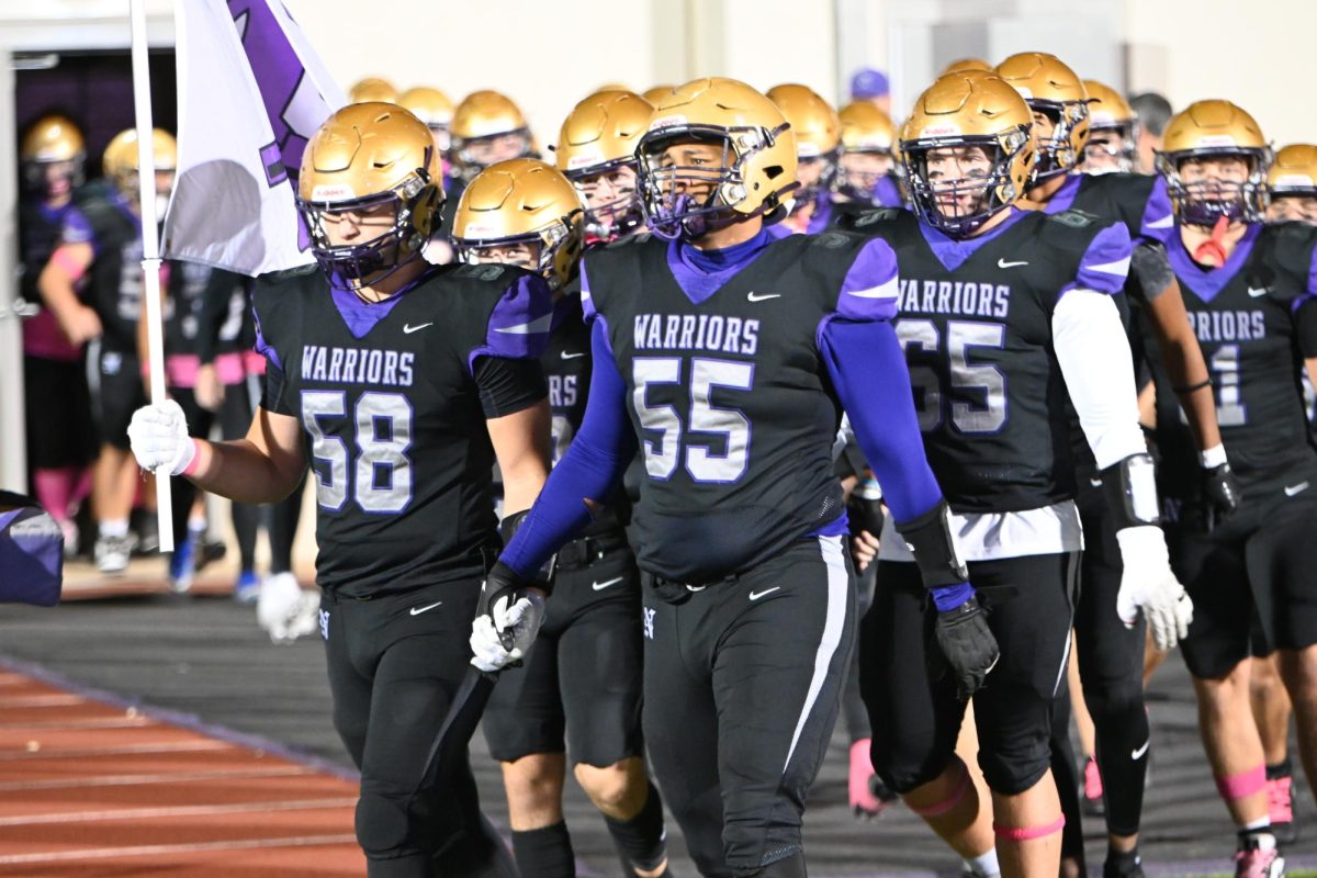 Seniors Harrison Tripp (left) and Kolton Borcherding-Johnson lead the Norwalk Warriors out of the locker room for their game against Glenwood. The Warriors went on to win the game 29-26.