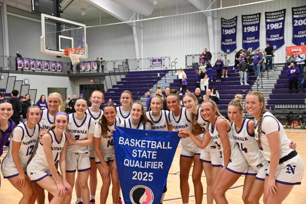 The girls basketball team poses with their state qualifier banner after their game on Tuesday. Norwalk defeated Pella 85-56.