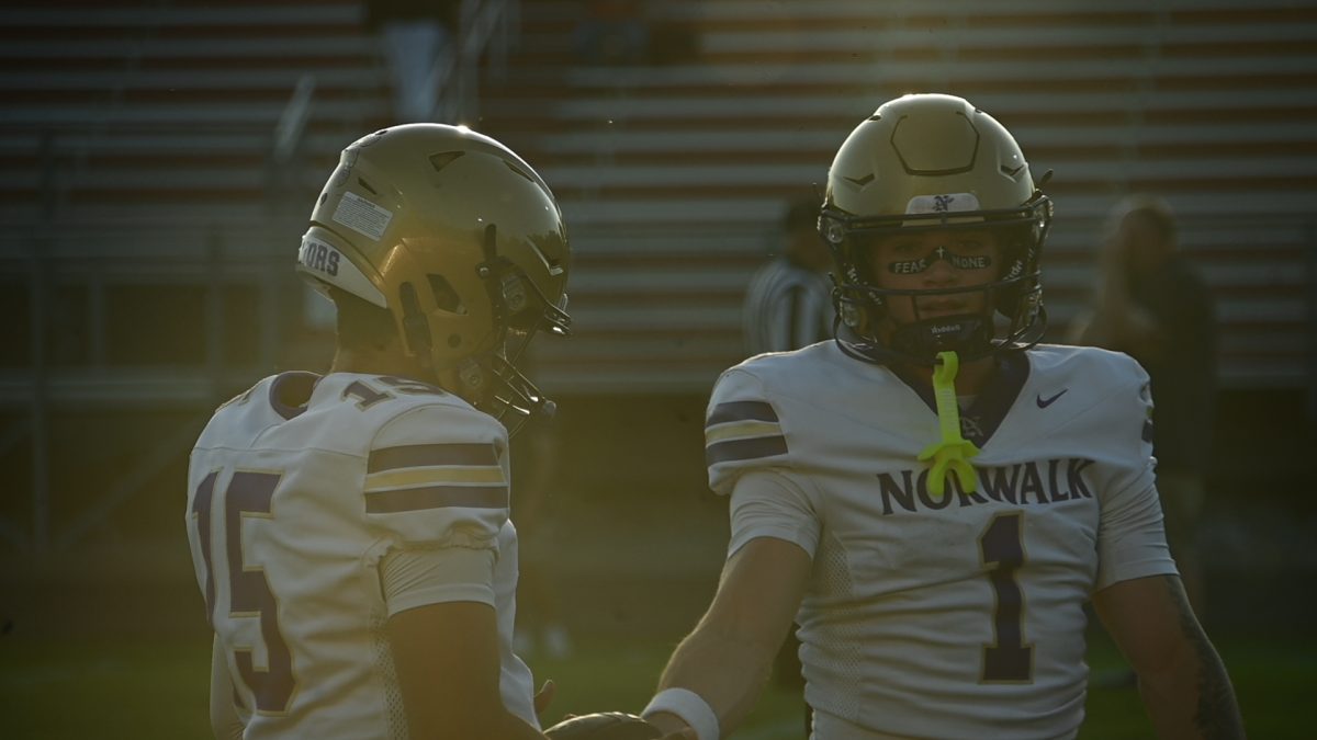 Eli Robbins (1) hands the ball to Abbas Mangal during warmups last Friday. Robbins broke the Norwalk career receiving record during the game.