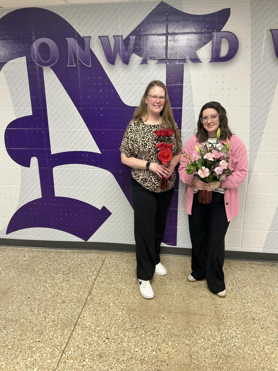 Mrs. Sleeth (left) and Mrs. Deters pose outside the main office recently with flowers they received for Valentine's Day. Students had both positive and negative things to say about the holiday.