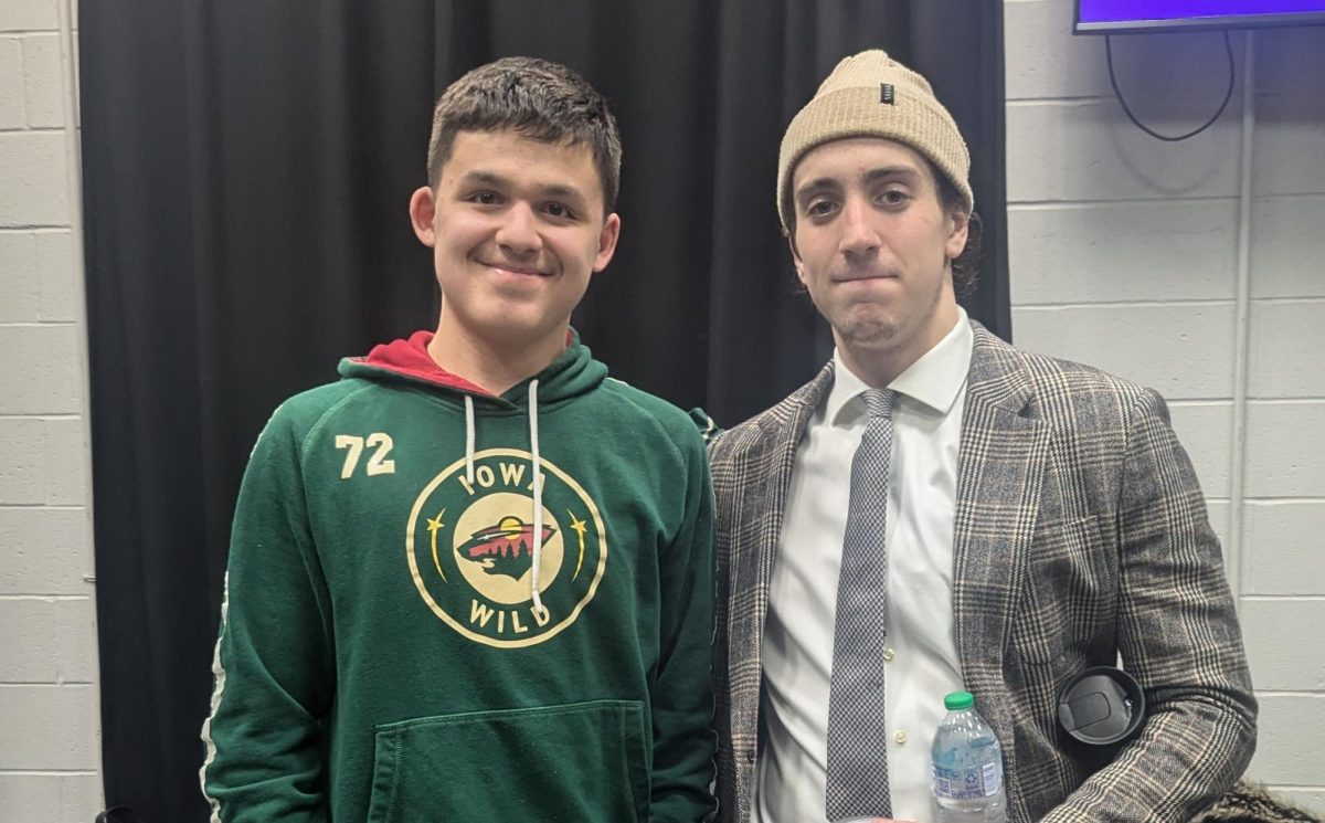 Student Gavin Briar (left) poses for a photo with Iowa Wild hockey player Carson Lambos.